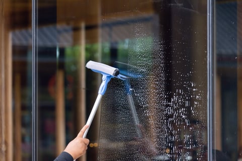 Professional exterior window cleaning with squeegee on glass