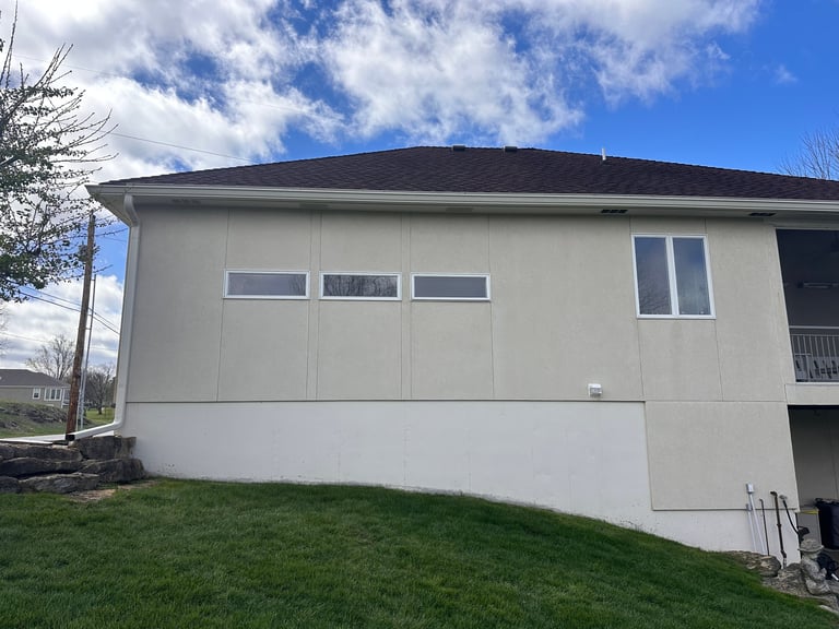 Modern two-car garage with cream-colored paneling and dark roof attached to residential home on grassy lot
